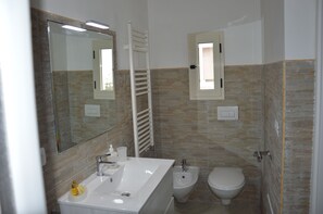 Ein Badezimmer mit Waschbecken, Bidet, Toilette, Spiegel und Handtuchhalter.