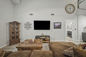 A living room with a television, clock, and framed picture. - NEW!! 2-bedroom Condo in Tranquil Chandler with cool AC (Chandler)