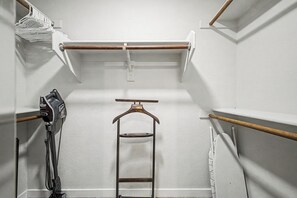 A closet with a wooden hanger rod, a vacuum cleaner, and a metal drying rack. - NEW!! 2-bedroom Condo in Tranquil Chandler with cool AC (Chandler)