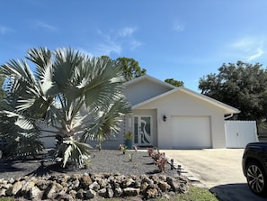 Ein Wohnhaus mit Garage, einer Palme und einem Schotterweg.