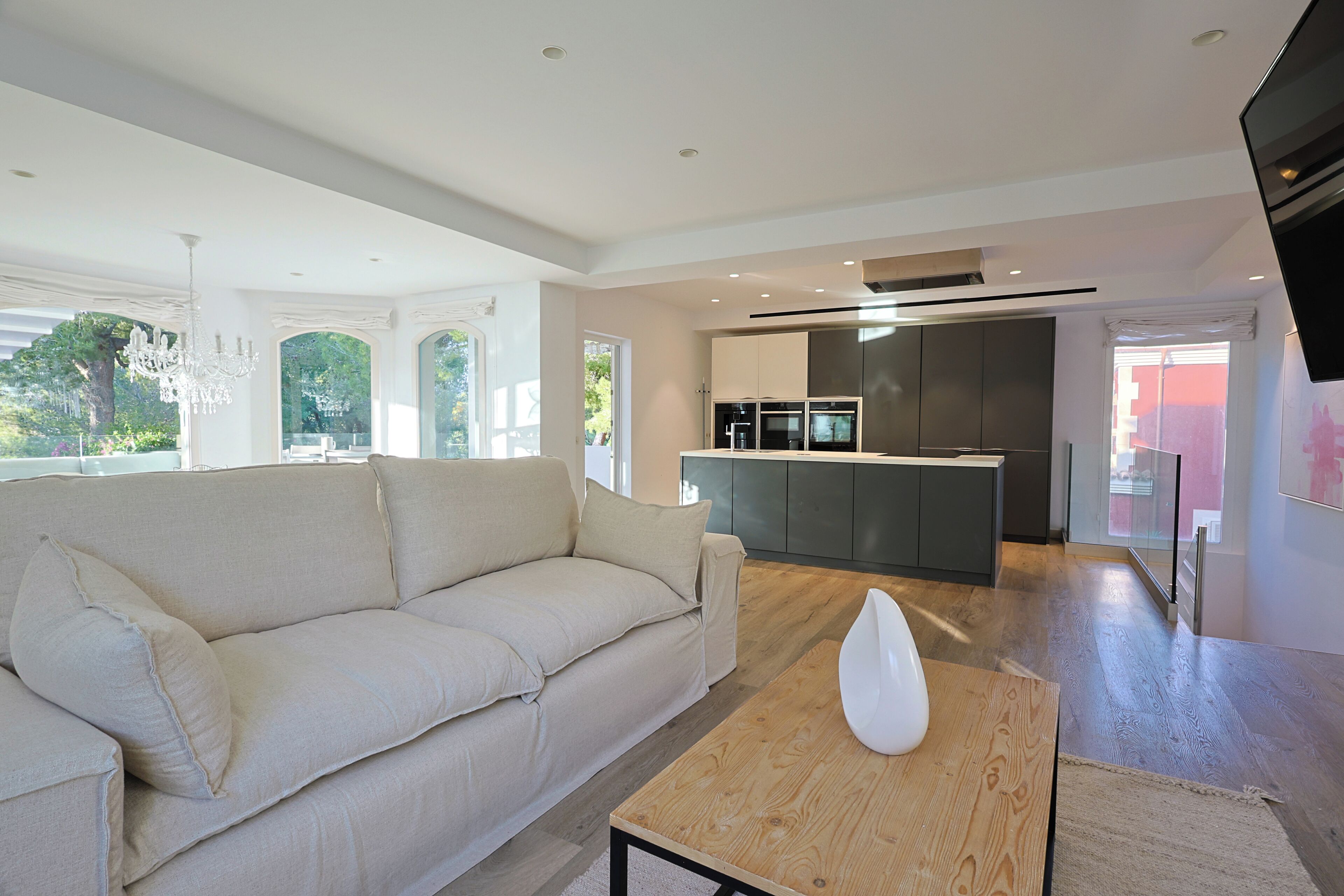 A modern living room with a sofa, a wooden coffee table, and a kitchen area in the background.