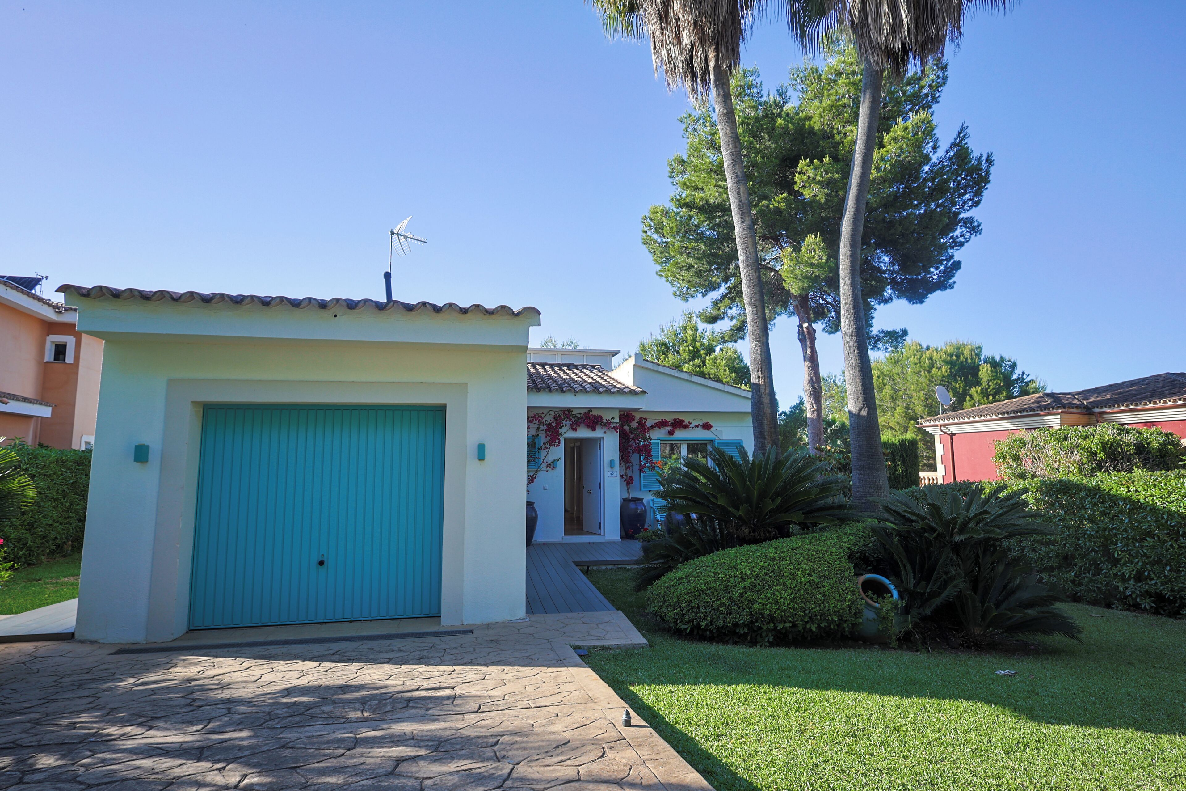 A residential house with a blue garage door, a tiled roof, and a well-maintained lawn.