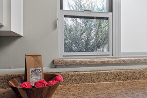 A kitchen counter with a brown paper bag labeled 'The NACS' and a wooden bowl containing pink flowers.