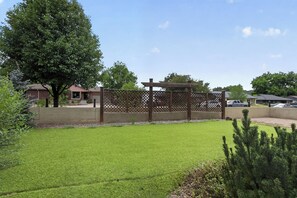 A residential property with a well-maintained lawn, a wooden fence, and a house in the background.