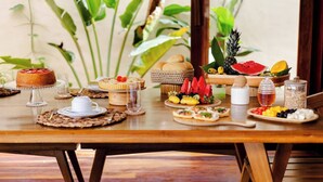 Ein Holztisch mit verschiedenen Speisen, darunter Kuchen, Obst und ein Glas Wasser.