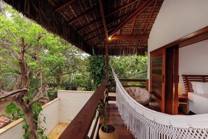 A hammock chair on a wooden balcony with a thatched roof, surrounded by lush greenery. - Deluxe Villa Luz Do Mar, rooftop Jacuzzi, sea view (Jijoca de Jericoacoara)