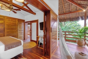 A room with wooden floors, a bed with a brown blanket, a ceiling fan, and a view of a balcony with a hammock and plants. - Deluxe Villa Luz Do Mar, rooftop Jacuzzi, sea view (Jijoca de Jericoacoara)