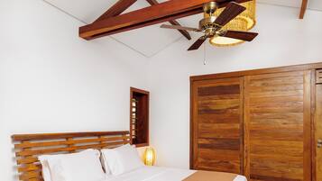 Quarto com cama de madeira, ventoinha no teto e um guarda-roupa de madeira grande.