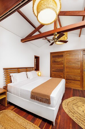 A bedroom with a wooden bed, a ceiling fan, and a large wooden wardrobe.