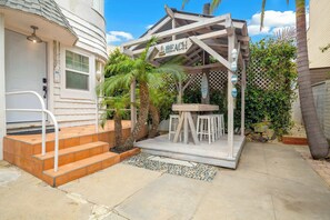 A covered outdoor seating area with a wooden pergola, a small table, and several chairs. - Mission Beach Bungalow w/ Direct Access to the Bay (San Diego)