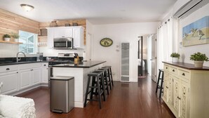 A modern kitchen with white cabinetry, stainless steel appliances, and a central island with stools. - Mission Beach Bungalow w/ Direct Access to the Bay (San Diego)