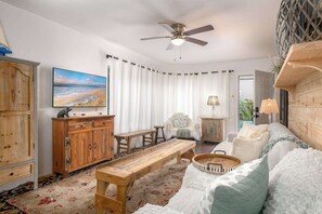 A cozy living room with a wooden bench, a television, and a ceiling fan. - Mission Beach Bungalow w/ Direct Access to the Bay (San Diego)