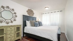 A bedroom with a bed, a dresser, a mirror, and a decorative sign on the wall. - Mission Beach Bungalow w/ Direct Access to the Bay (San Diego)
