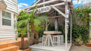 A wooden pergola with a sign reading 'Beach' and a table with chairs underneath. - Mission Beach Bungalow w/ Direct Access to the Bay (San Diego)
