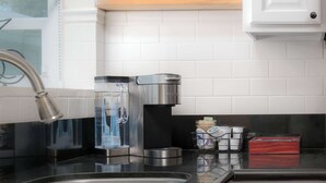 A kitchen with a coffee maker, a water dispenser, and a spice rack. - Mission Beach Bungalow w/ Direct Access to the Bay (San Diego)
