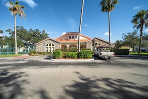 A two-story house with a stone facade, a red-tiled roof, and a driveway with a parked truck. - 15min from Disney - Spacious Starwars themed condo (Kissimmee)