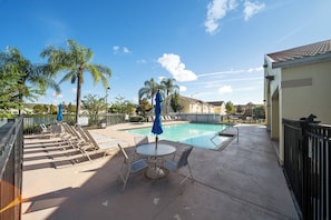 A pool area with lounge chairs, a table, and umbrellas.