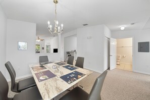 A conference room with a marble table, black chairs, a chandelier, and a door leading to a bathroom. - 15min from Disney - Spacious Starwars themed condo (Kissimmee)