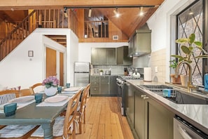 A modern kitchen with a dining area, wooden beams, and a view of the outdoors. - Cozy Masthope Chalet on 2 Private Wooded Acres w/ Grill, Fire Pit & Pet-Friendly (Lackawaxen)