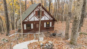 A cabin with a steep roof, wooden siding, and a front porch with two chairs. - Cozy Masthope Chalet on 2 Private Wooded Acres w/ Grill, Fire Pit & Pet-Friendly (Lackawaxen)