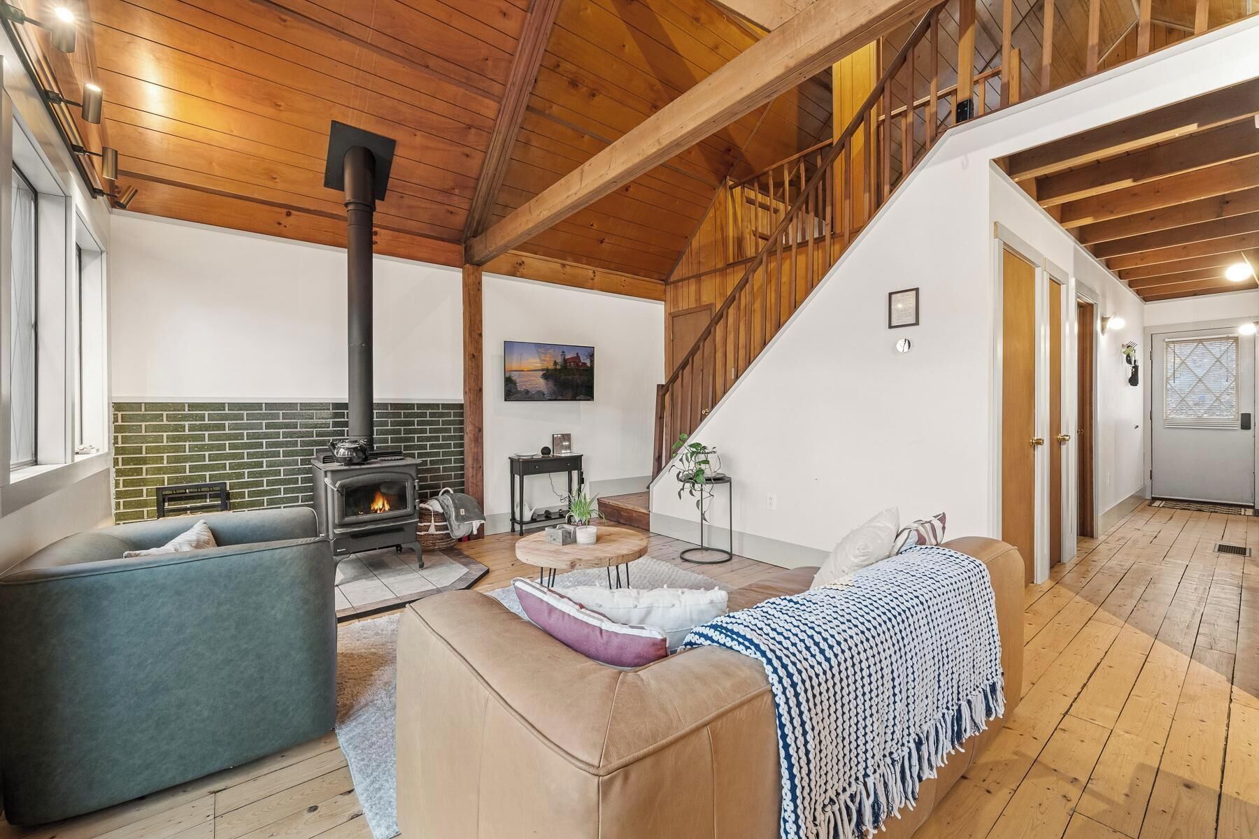 A spacious living area with a fireplace, a sofa, a coffee table, and a staircase leading to an upper level.