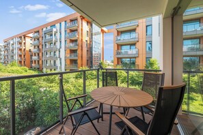 A balcony with a round table and chairs, overlooking a residential building with multiple balconies. - Brabank Comfort by Grand Apartments (Gdańsk)