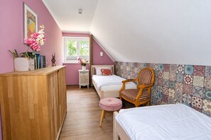 A bedroom with a wooden desk, two beds, a chair, and a window with curtains. - Vacation Rental Near the Sababurg Zoo: "Sleeping Beauty" Room (Hofgeismar)