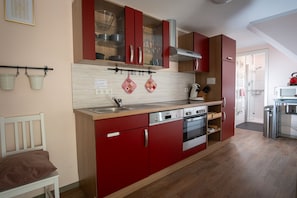 A compact kitchen with red cabinets, a built-in oven, and a microwave. - Vacation Rental Near Sababurg Zoo: Sleeping Beauty Room (Hofgeismar)