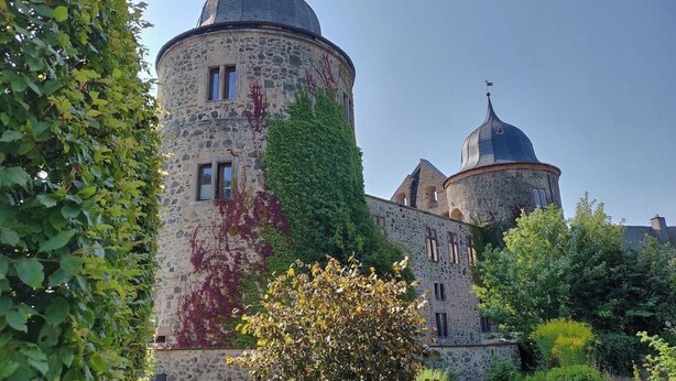 Ein historisches Steinhaus mit einem runden Turm und einer kleineren Kuppel.