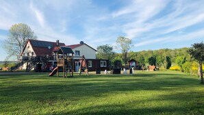 Ein Wohnhaus mit großem Garten, einem Spielbereich und einem gepflegten Rasen.