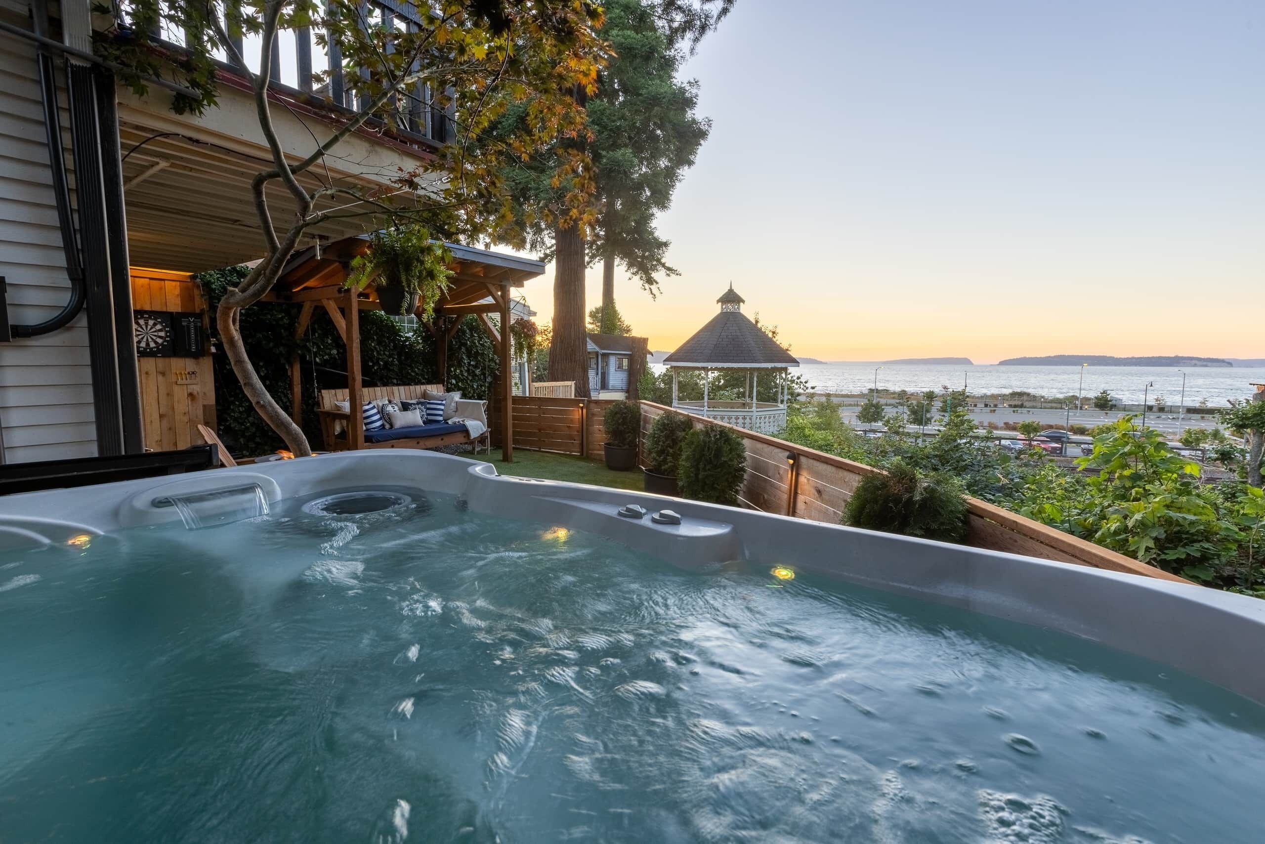 A hot tub with a view of the sea, a gazebo, and a wooden deck.