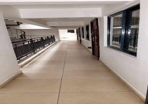 A corridor with a tiled floor, a railing on one side, and a window on the other. - Wonderful studio apartment in Nairobi perfect for your next getaway (Nairobi)