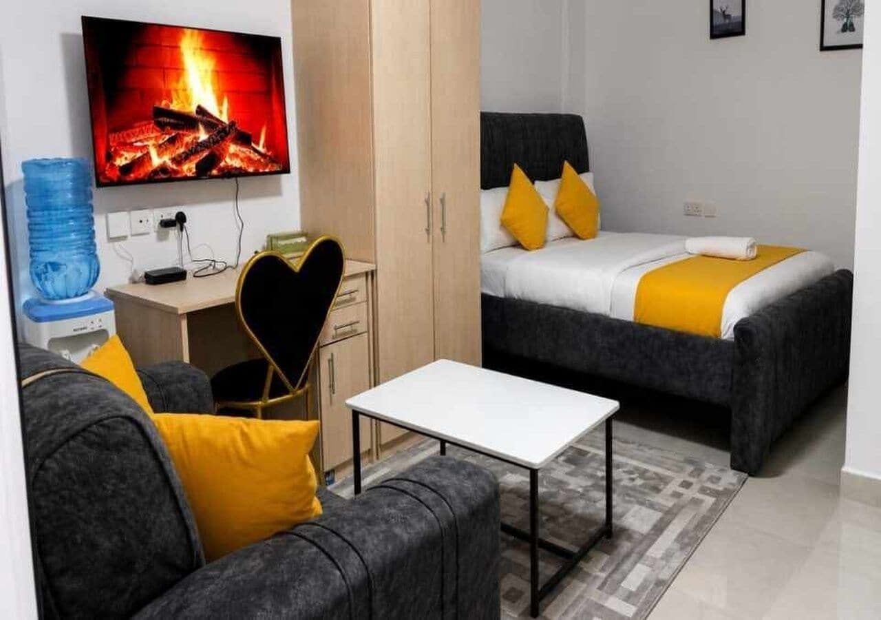 Een knus woongedeelte met een bed, bank, televisie en een klein tafeltje.