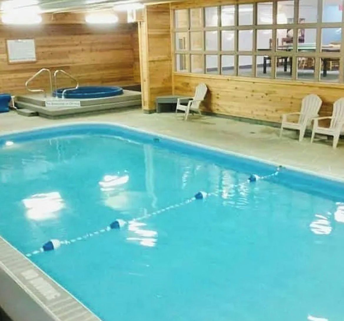 An indoor swimming pool with a wooden wall, a window, and a lifeguard stand.