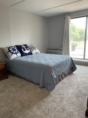 A bedroom with a bed, a nightstand, a window with curtains, and a view of greenery outside. - Anchor Stay!  Condo w/larger deck overlooking harbor, sleeps up to 6 (Clear Lake)