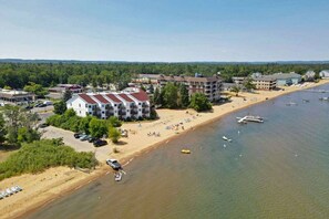 Un hôtel situé sur la côte, composé de plusieurs bâtiments, avec une plage de sable et des bateaux amarrés dans l’eau.
