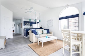A modern living room with a sofa, coffee table, and dining area. - Oasis 321 | Beachfront Condo | Downtown + Tart Trail (Traverse City)