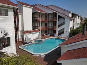 A hotel with a swimming pool, balconies, and a covered patio area. - Oasis 321 | Beachfront Condo | Downtown + Tart Trail (Traverse City)