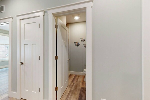 A hallway with a door leading to a bathroom with a shower and toilet.