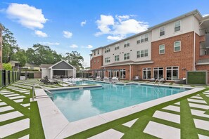 A modern outdoor pool area with multiple pools, surrounded by a brick building with balconies. - Tuscaloosa Retreat ~ Minutes to Bryant-Denny (Tuscaloosa)