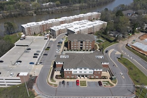 A multi-story building with a parking lot and a river in the background. - Tuscaloosa Retreat ~ Minutes to Bryant-Denny (Tuscaloosa)