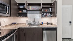 Una cucina moderna con mobili in legno scuro, lavastoviglie in acciaio inossidabile e un forno a microonde.
