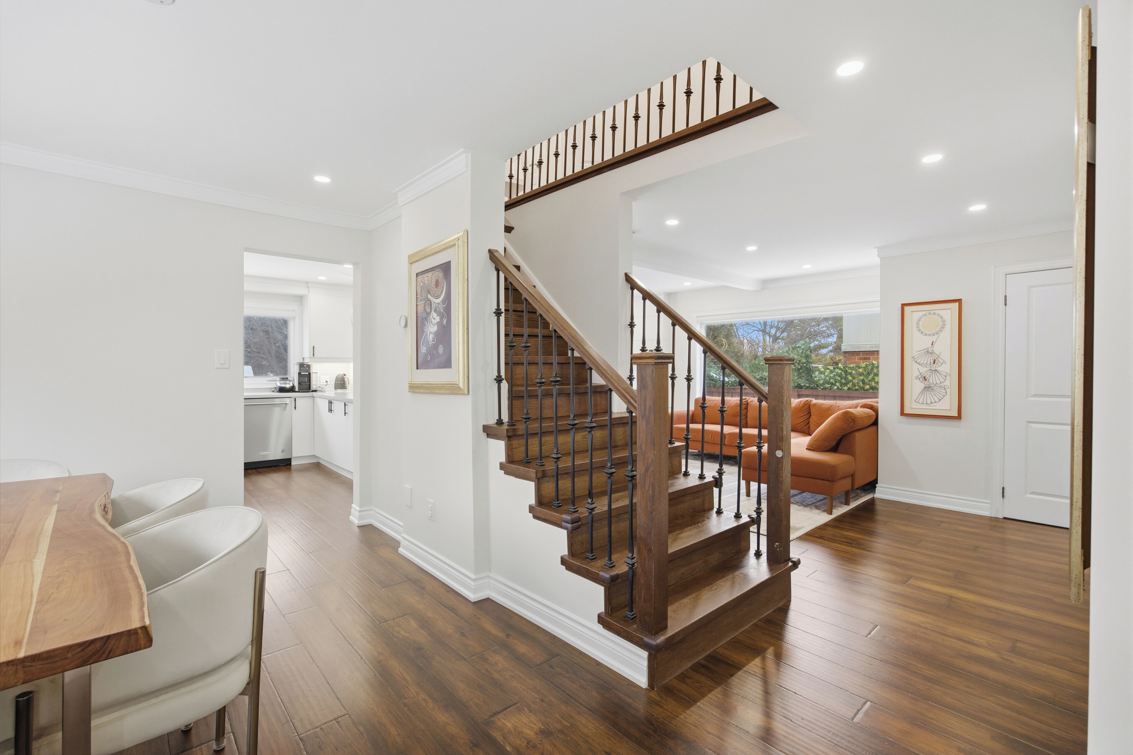 Ein modernes Interieur mit einer Holztreppe, einem Essbereich und einem Wohnzimmer mit einer Couch.