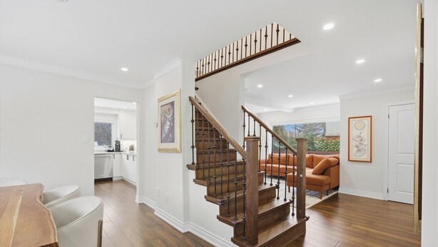 Un interior moderno con una escalera de madera, un comedor y una sala de estar con sofá.