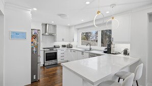 Una cocina moderna con armarios blancos, electrodomésticos de acero inoxidable y una isla grande con asientos.