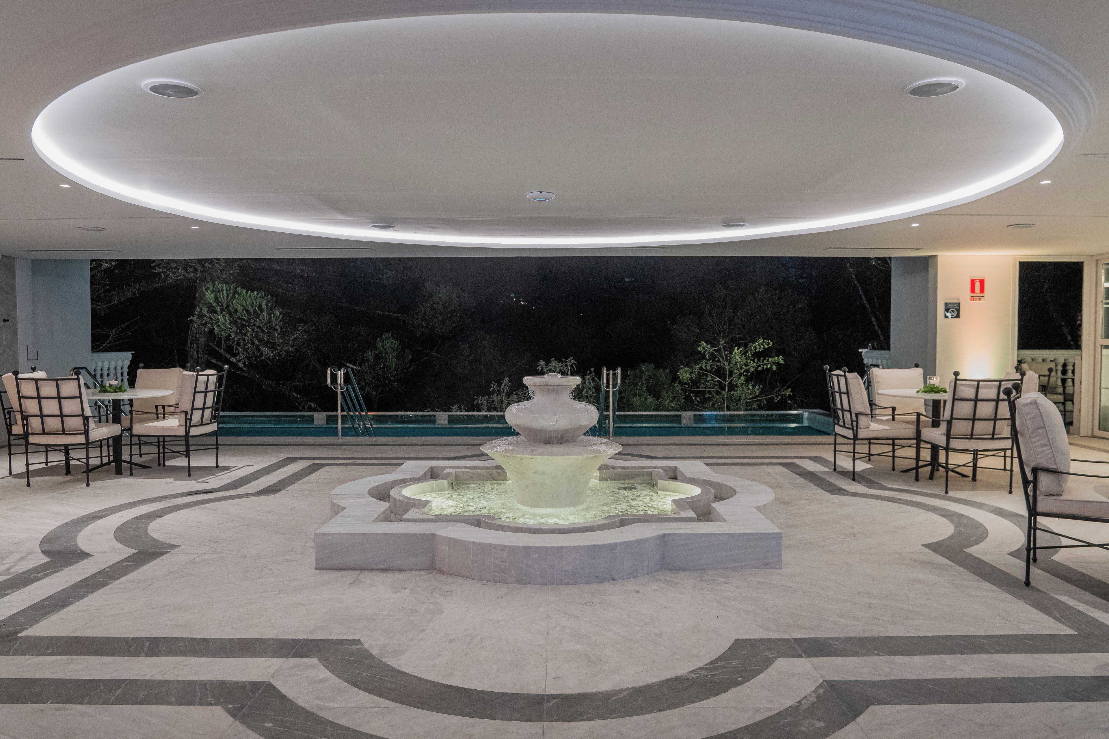 A lobby with a central fountain, seating area, and a view of the outdoors.