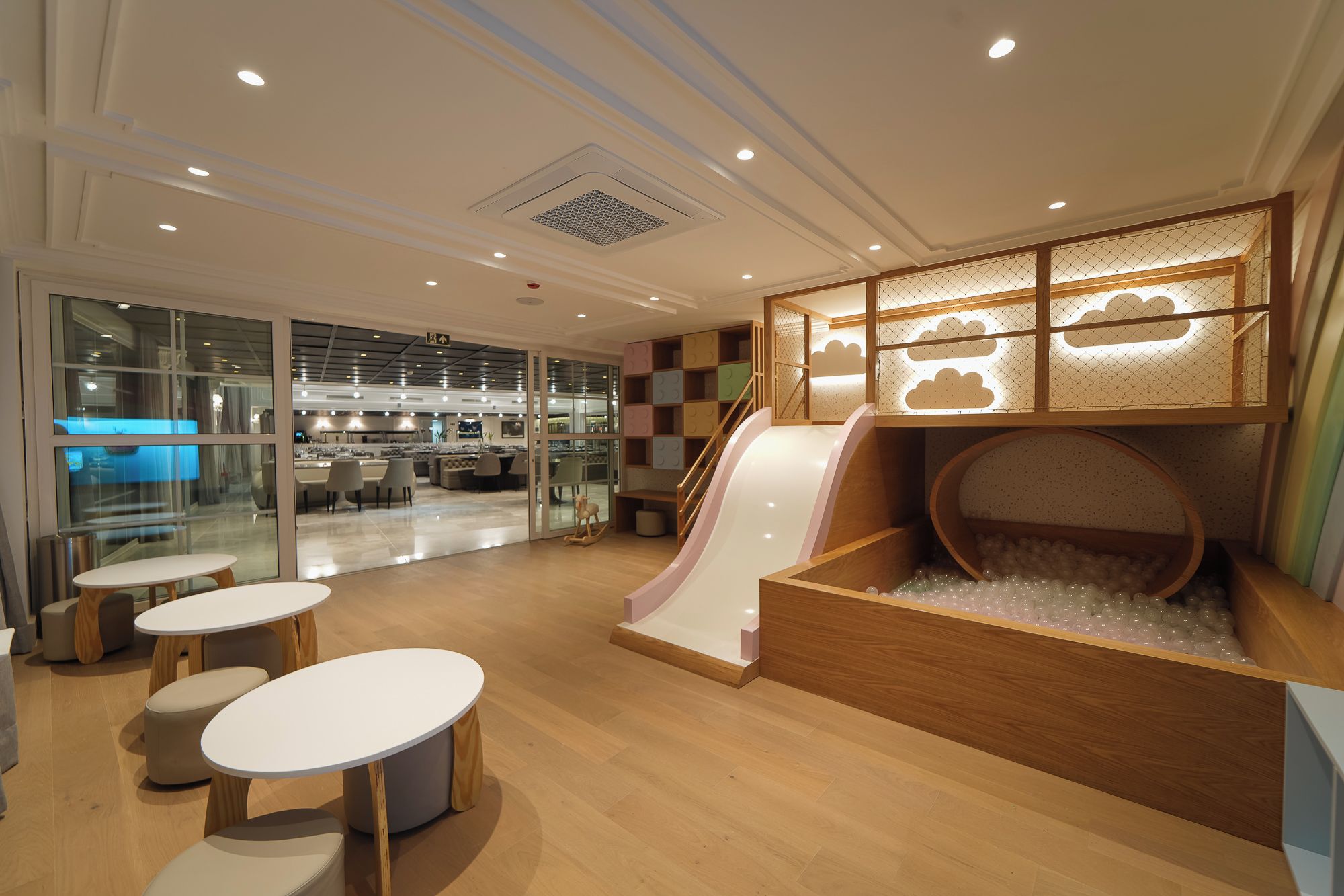 Un espace de jeux pour enfants avec un toboggan, des sièges et un parc avec une piscine à balles.