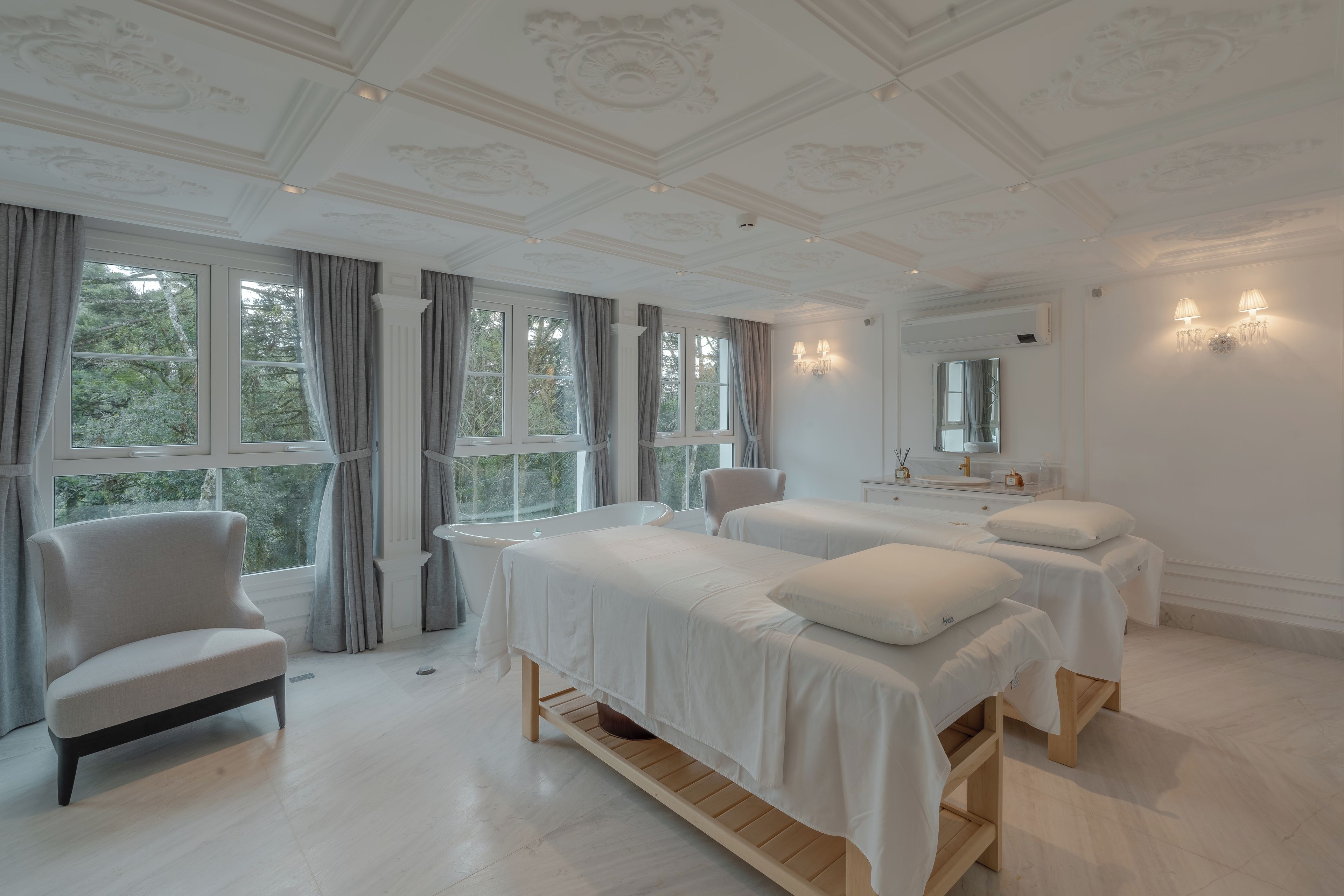 A bedroom with two beds, a chair, and a large window.