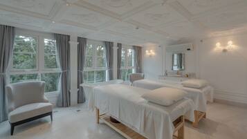 A bedroom with two beds, a chair, and a large window.