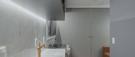 A modern kitchen with a white countertop, a gold faucet, and a built-in oven.